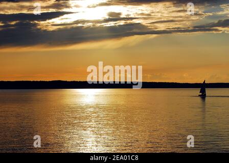 Un voilier isolé baignait dans la lumière dorée du soleil pendant le coucher du soleil Banque D'Images