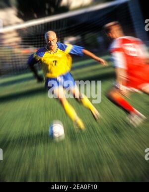 Deux jeunes hommes jouant au football. Effet de flou/zoom. Banque D'Images