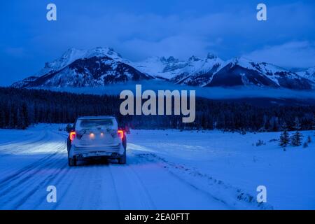 4x4 sur route verglacée et enneigée pendant un blizzard ou hiver tempête de neige avec un beau Paysage montagneux du Canada de Banff N. Banque D'Images