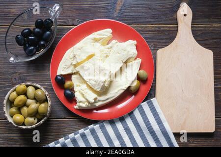 Cuisine des Balkans. Monténégro. Le fromage Pljevaljski est un fromage blanc doux local dans une assiette rouge sur une table rustique sombre. Copier l'espace Banque D'Images