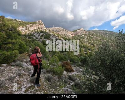 Femme randonneur avec sac à dos rouge photographiant les paysages de montagne, Mt Hymettus, près d'Athènes, Grèce Banque D'Images