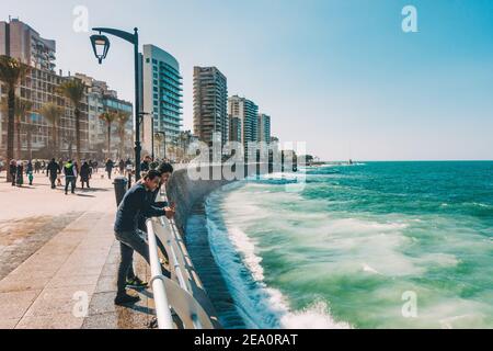 Deux hommes font une pause pour regarder les vagues un après-midi sur la corniche de Beyrouth, au Liban Banque D'Images