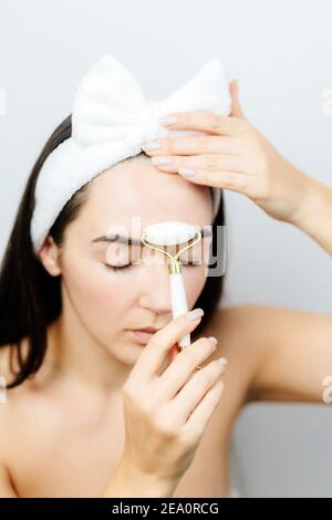 Portrait d'une femme utilisant un rouleau facial pour le massage du visage de la peau soins Banque D'Images