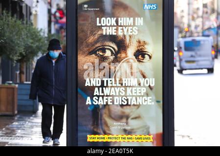 Londres, Royaume-Uni. 02 février 2021. Un homme portant un masque passe devant une affiche de campagne publicitaire du NHS Covid-19 à Londres. Le gouvernement britannique a déclaré qu'il vaccine plus de 50 ans d'ici mai 2021. Crédit : SOPA Images Limited/Alamy Live News Banque D'Images