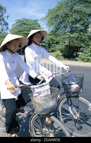 Asie, Vietnam, delta du Mékong, jolies jeunes étudiantes portant une robe traditionnelle vietnamienne Aoi- Dai à vélo à l'école Banque D'Images