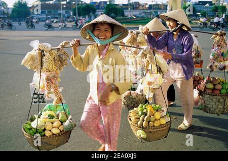 Vietnam, Ho Chi Minh ville aka Saigon, groupe de femmes vietnamiennes vendeurs transportant des produits au marché Banque D'Images