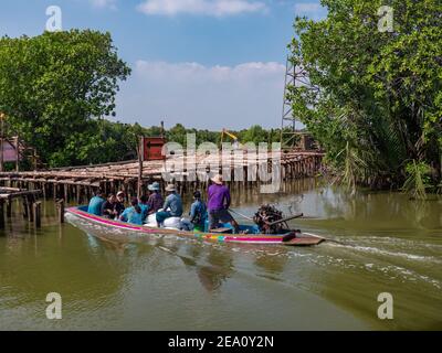 Les agriculteurs locaux passent devant un chantier de construction où un pont routier est en cours de construction, sur un bateau traditionnel thaïlandais à longue queue, sur un canal entre crevettes et shellfis Banque D'Images