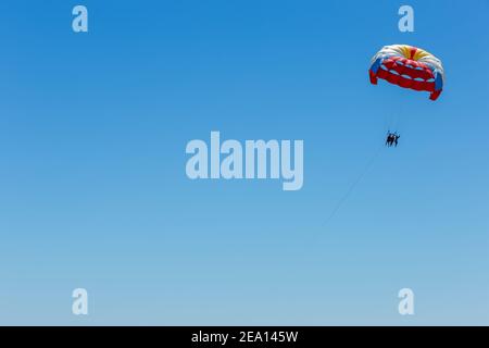 Les parachutistes volent dans le ciel bleu. Location de parachutes Banque D'Images