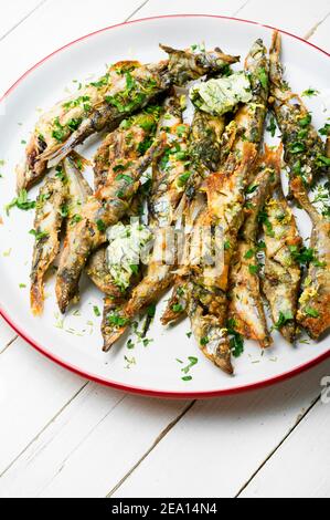 Poisson frit au capelan avec des herbes. Poisson frit au capelan sur l'assiette Banque D'Images