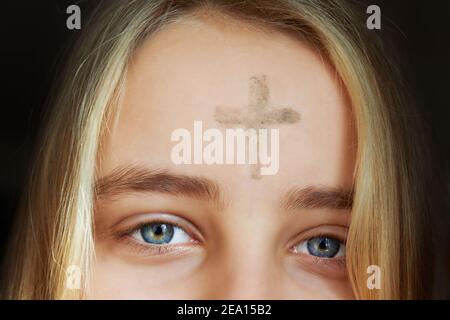 Fille avec croix faite de cendres sur le front. Concept de mercredi de cendres. Banque D'Images