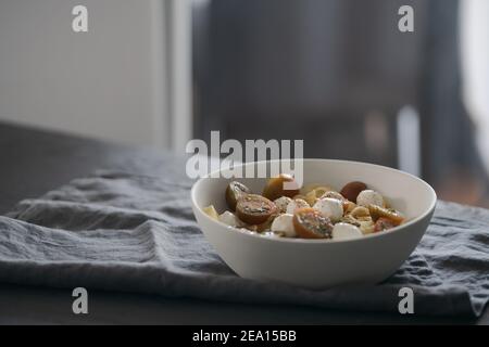 Fettuccine avec mozzarella, tomates et pesto dans un bol blanc sur table noire, photo peu profonde Banque D'Images