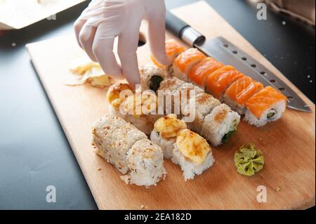 Le chef cuisent des sushis. Chef prend des sushis d'une main dans des gants. Banque D'Images