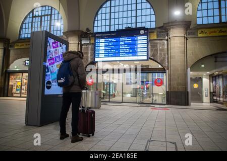 Hagen, Allemagne. 07e février 2021. Un homme se tient devant le tableau d'affichage montrant les retards et les annulations de train à la gare principale et regarde son smartphone. Pendant la nuit, il y a eu de fortes chutes de neige dans de grandes parties de la Rhénanie-du-Nord-Westphalie. Credit: Jonas Güttler/dpa/Alay Live News Banque D'Images