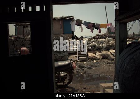 Un enfant descend dans les escaliers de sa maison dans la région de Muara Baru, dans la zone côtière de Jakarta, Indonésie. Plusieurs maisons de la région ont été construites au-dessus de l'eau de mer sur pilotis, juste à l'extérieur de la structure de protection côtière reliant la communauté avec une route côtière et leurs voisins terrestres. Muara Baru, Penjaringan, Nord de Jakarta, Jakarta, Indonésie. Photo d'archive. Banque D'Images