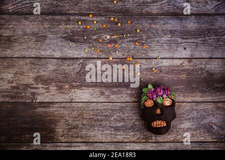 Biscuit de pain d'épice peint à la main crâne d'Halloween effrayant avec des saupoudrés de couleur sur fond de bois. Vue de dessus. Pose à plat. Copier l'espace Banque D'Images