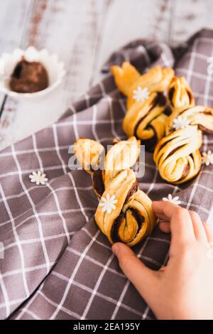 Les enfants prennent à la main de délicieux palmiers avec du chocolat sur fond de bois. Concept de Pâques, lapin Banque D'Images