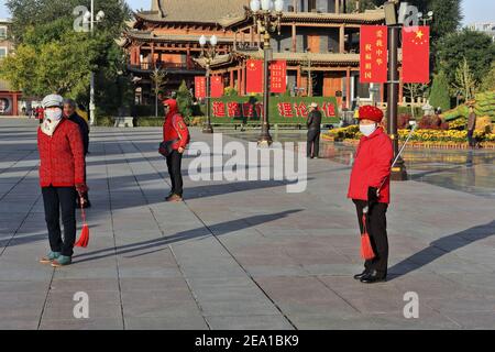 Groupe de praticiens taijian-sabre tai chi au soleil du matin réalisez des chorégraphies d'escrime au son de la musique portable comme si l'entretien doit être effectué Banque D'Images