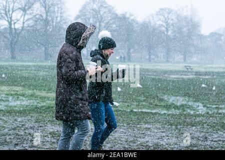 WIMBLEDON LONDRES, ROYAUME-UNI 7 FÉVRIER 2021. Les gens qui marchent à travers Wimbledon Common pendant une douche de neige alors que Storm Darcy arrive au Royaume-Uni ce matin avec des températures glaciales. Le met Office a émis des avertissements de neige et de glace jaunes et des chutes de neige perturbatrices dans le sud-est de l'Angleterre avec des gales froides de 50 km/h en provenance de Russie et d'Ukraine surnommés « mini Beast from the EastCredit: amer ghazzal/Alamy Live News Banque D'Images