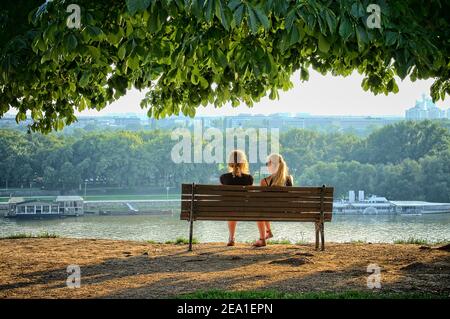 BELGRADE, SERBIE - 29 JUILLET 2014 : deux jeunes femmes assises sur un banc de la forteresse de Kalemegdan, en face des fleuves du Danube. Tourné en 2014 Banque D'Images