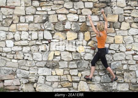 BELGRADE, SERBIE - 29 JUILLET 2014 : une jeune femme entraîne l'escalade urbaine sur un mur de la forteresse de Kalemegdan à Belgrade. Tourné en 2014 Banque D'Images