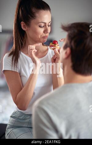 Un jeune homme appréciant de nourrir sa petite amie le matin dans une atmosphère gaie à la maison. Couple, amour, petit déjeuner, ensemble Banque D'Images