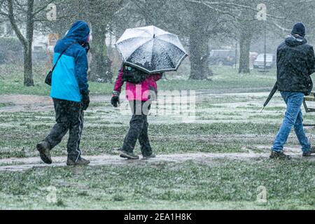 WIMBLEDON LONDRES, ROYAUME-UNI 7 FÉVRIER 2021. Des piétons traversent Wimbledon Common lors d'une averse de neige alors que Storm Darcy atteint le Royaume-Uni ce matin avec des températures glaciales. Le met Office a émis des avertissements de neige et de glace jaunes et des chutes de neige perturbatrices dans le sud-est de l'Angleterre avec des gales froides de 50 km/h en provenance de Russie et d'Ukraine surnommés « mini Beast from the East Credit: amer ghazzal/Alamy Live News Banque D'Images