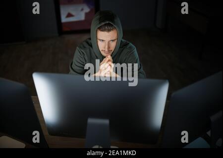 Un hacker mâle sérieux dans le capot fonctionne sur l'ordinateur Banque D'Images