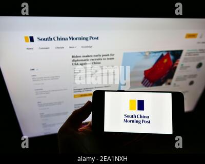 Personne tenant un smartphone avec le logo du journal South China Morning Post (Hongkong) sur l'écran devant le site Web de l'entreprise. Mise au point sur l'affichage du téléphone. Banque D'Images