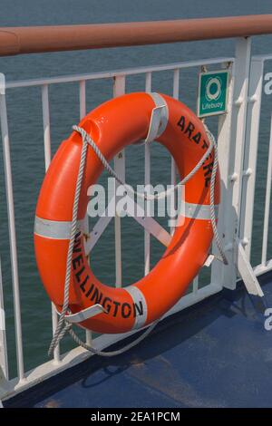 Ceinture de sécurité orange sur le pont du traversier du détroit de Cook avec cordon de sécurité. Dispositif de flottement de sécurité fixé sur les rambardes en cas de chute d'une personne Banque D'Images