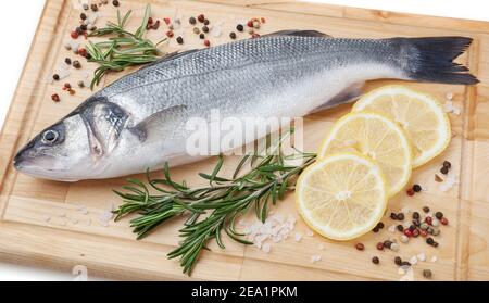 Brochet frais non cuit avec citron, romarin et épices sur bois sur fond blanc Banque D'Images