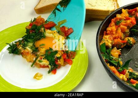La spatule de cuisine ajoute les œufs frits shakshuka dans la sauce aux légumes. Cuisine juive et arabe. Petit déjeuner sain et nutritif. Gros plan. Cuisine maison Banque D'Images
