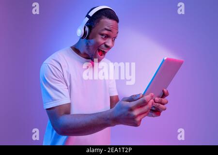 Offre en ligne. Black Guy dans un casque tenant une tablette numérique avec écran lumineux Banque D'Images