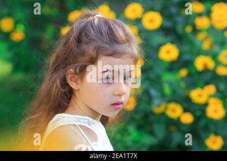 Portrait d'une petite fille triste et mignonne qui a l'air triste et peur au parc d'été Banque D'Images