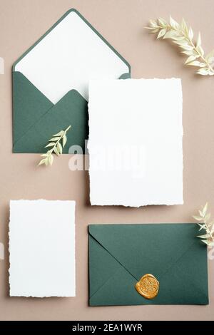 Papeterie de mariage vintage vue du dessus. Enveloppes vertes plates avec cachet à la cire, cartes en papier vierges, fleurs séchées. Motif invitation à un mariage. Banque D'Images