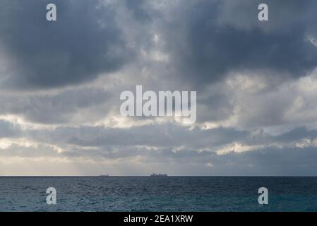 Navire solitaire à l'horizon au milieu de la mer avec de lourds nuages Banque D'Images