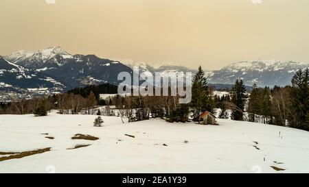 Paysage de neige avec sable du Sahara dans l'air. Arbres sur la pente enneigée, forêts et haute lande. Hiver mit Saharasand à Wolke. Alpsteinmassif, Amerlügen Banque D'Images