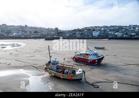 Vue panoramique sur de nombreux bateaux de pêche et d'autres posés sur le sable dans le port de St Ives. Vide et calme en raison du confinement global en cas de pandémie Covid-19 Banque D'Images