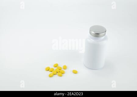 Flacon de pilules avec des pilules jaunes isolées sur fond blanc. Banque D'Images