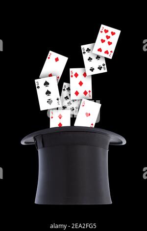 Les cartes à jouer se déversent et sont dispersées d'un chapeau noir à l'envers sur fond noir. Concept magicien isolé sur fond noir. Banque D'Images
