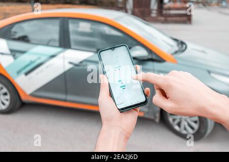 11 mai 2020, Ufa, Russie: Un jeune sur un smartphone réserve une voiture dans l'application de partage de voitures Delimobil pour se déplacer dans la ville. La nouvelle génération choisit de ne pas le faire Banque D'Images