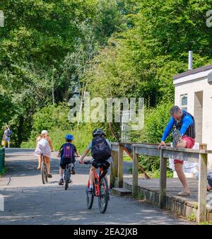 Trois enfants font du vélo et l'homme s'étire devant le club de ski nautique de Rickmansworth, à Rickmansworth Aquadrome, dans le Hertfordshire, au Royaume-Uni. Banque D'Images