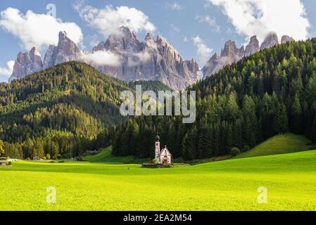 Paysage d'automne des Dolomites avec la chapelle de Ranui à Villnöss en face des forêts et des rochers des pics de Puez-Odle au soleil, Tyrol du Sud Banque D'Images