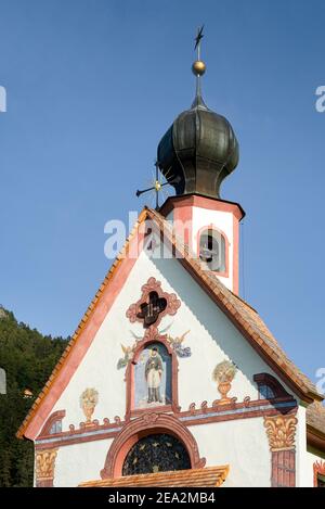 Façade et clocher de la chapelle Baroque de Ranui à Villnöß en face des montagnes de Puez-Odle dans les Dolomites au soleil, Puez-Geisler, Tyrol du Sud, Italie Banque D'Images