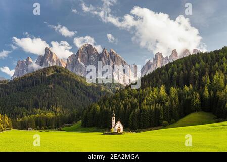 Paysage d'automne des Dolomites avec la chapelle de Ranui à Villnöss en face des forêts et des rochers des pics de Puez-Odle au soleil, Tyrol du Sud Banque D'Images