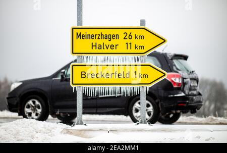 Breckerfeld, Allemagne. 07e février 2021. Les icicles pendent d'un panneau en direction de Breckerfeld, Meinerzhagen et Halver comme une voiture passe. Après de fortes chutes de neige dans de grandes parties de la Rhénanie-du-Nord-Westphalie pendant la nuit, des pluies verglaçantes sont tombées dans l'après-midi. Credit: Jonas Güttler/dpa/Alay Live News Banque D'Images