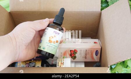 Alicante, Espagne - janvier, 2021: IHerb site suppléments et beauté naturel produits emballage. Femme main tenant l'huile d'argan Banque D'Images