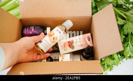 Alicante, Espagne - janvier, 2021: IHerb site suppléments et beauté naturel produits emballage. Femme tenant main l'huile d'abricot Banque D'Images