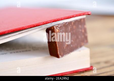 chocolat avec noix entre les pages d'un vieux livre. Banque D'Images