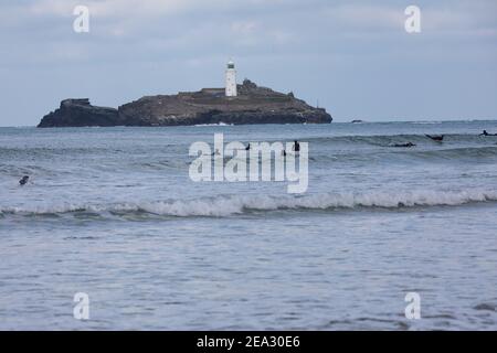 Surfeurs vus de St Gothian Sands à Cornwall, Royaume-Uni Banque D'Images