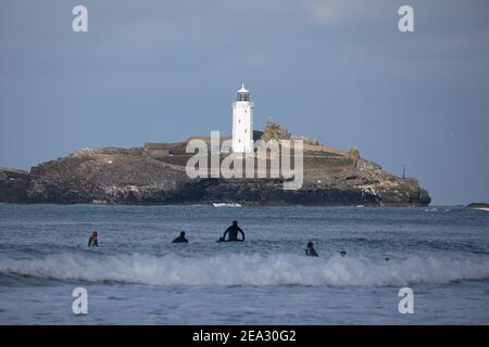 Surfeurs vus de St Gothian Sands à Cornwall, Royaume-Uni Banque D'Images